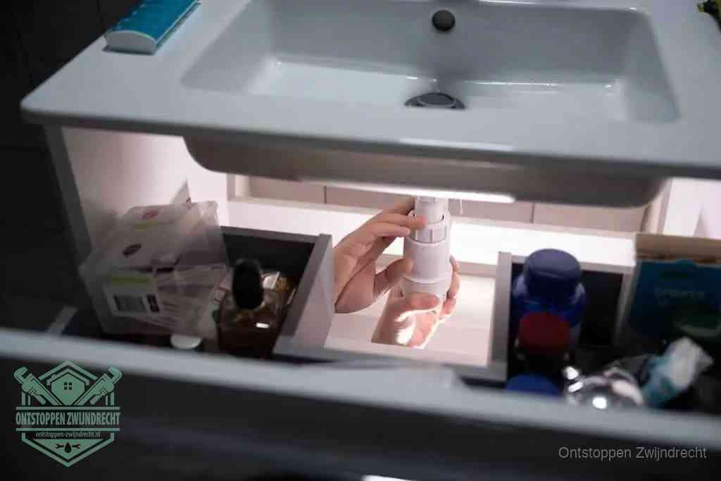 Een pompfles met zeep boven een wastafel, de heet water en afwasmiddel-methode om een vetprop in de afvoer los te maken in Zwijndrecht