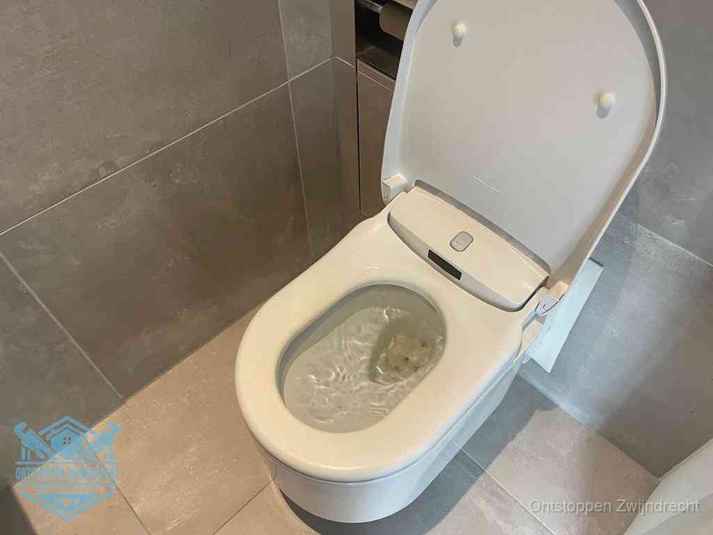 Een toiletpot vol troebel water met drijvend papier en restanten, de meest voorkomende oorzaak van een verstopte wc in Zwijndrecht