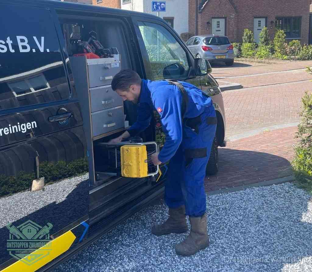 Een monteur pakt buiten op de oprit gereedschap uit de bedrijfsbus, het moment om een professional in te schakelen voor een verstopte afvoer in Zwijndrecht
