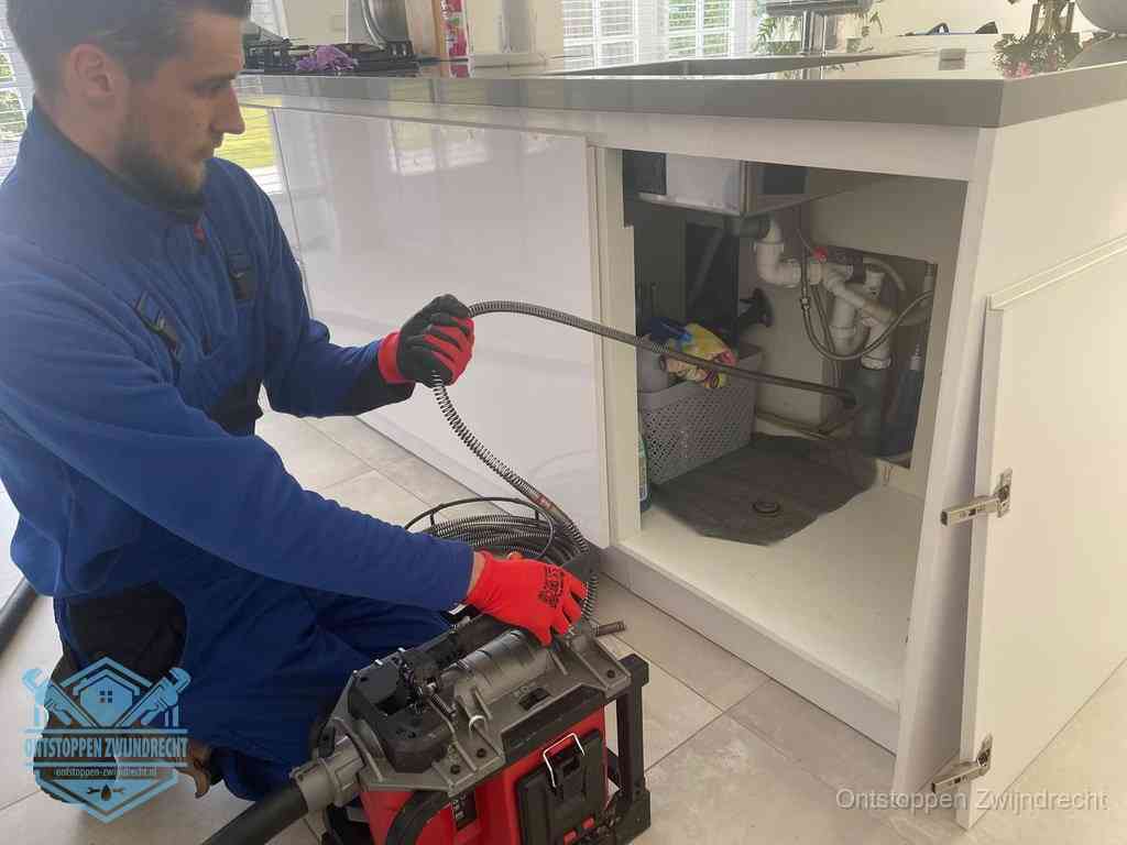 Een monteur reinigt de keukenafvoer grondig met een veermachine om terugkerende gootsteenverstoppingen te voorkomen in Zwijndrecht