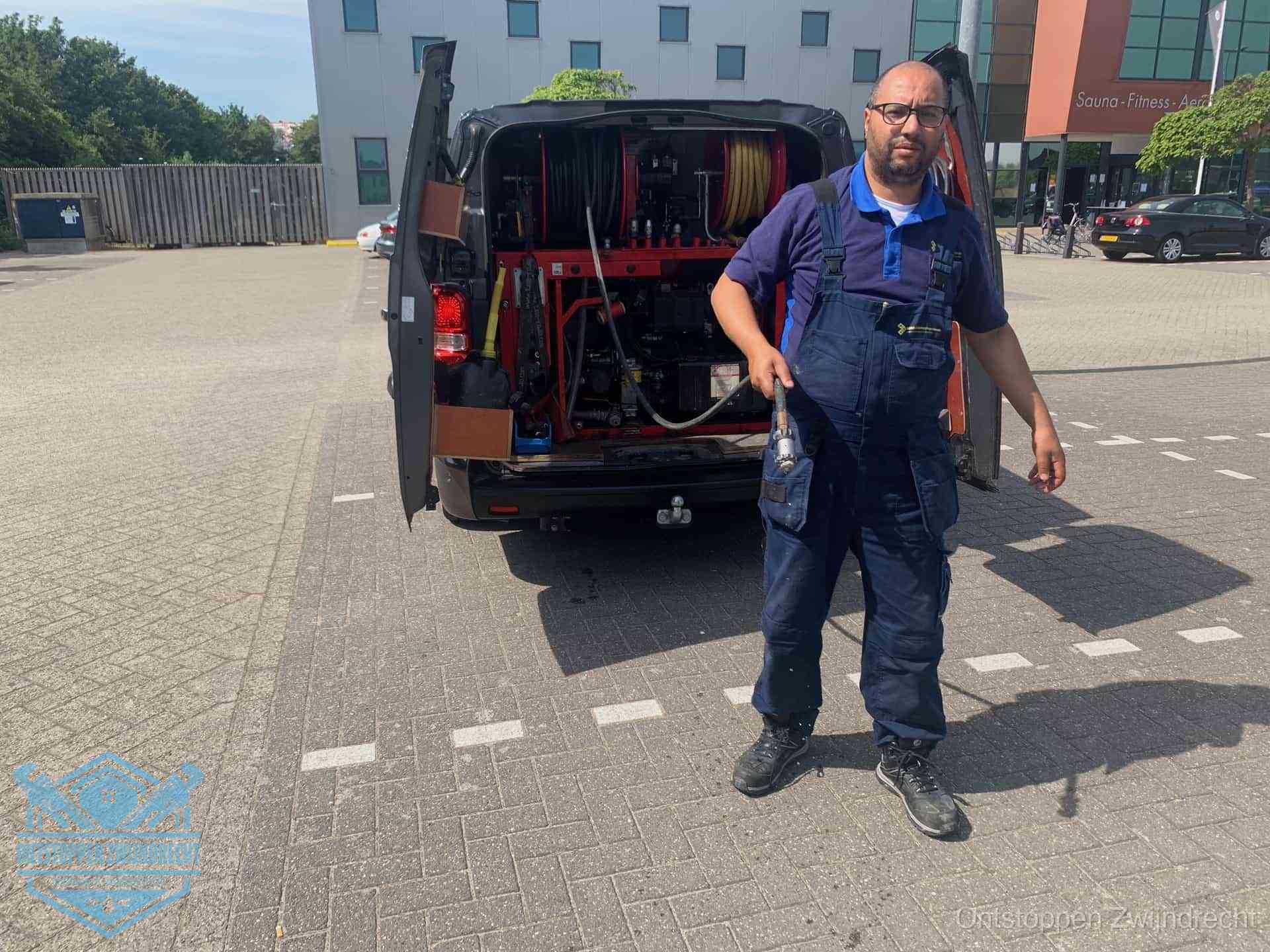 Een monteur bij zijn bestelbus met een hogedruk- en rioolreinigingsunit, klaar om de oorzaak van terugkerende wc-verstoppingen aan te pakken in Zwijndrecht
