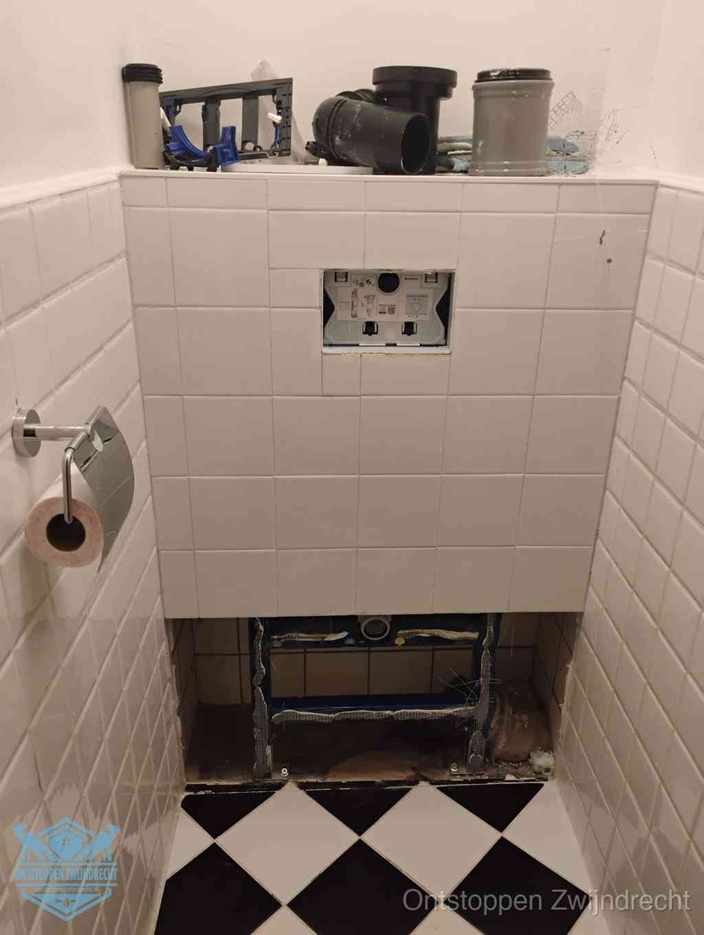 Een toiletruimte waar het hangtoilet en de inbouwreservoir-onderdelen zijn vrijgelegd voor onderhoud, periodiek nazicht voorkomt een wc-verstopping in Zwijndrecht